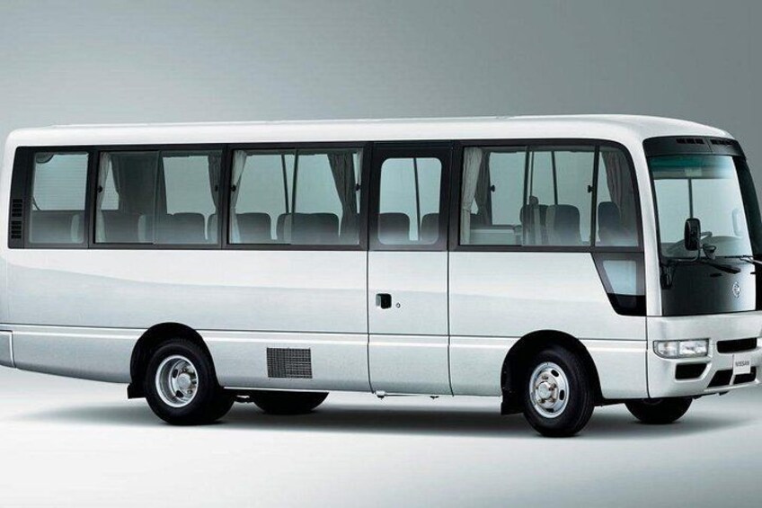 A white bus with a front windshield, side windows, and a rear section with seats. 1