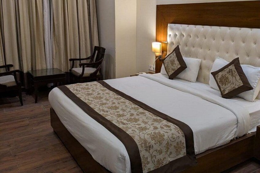 A neatly made bed with a patterned bedspread, a wooden headboard, and two bedside lamps. 2