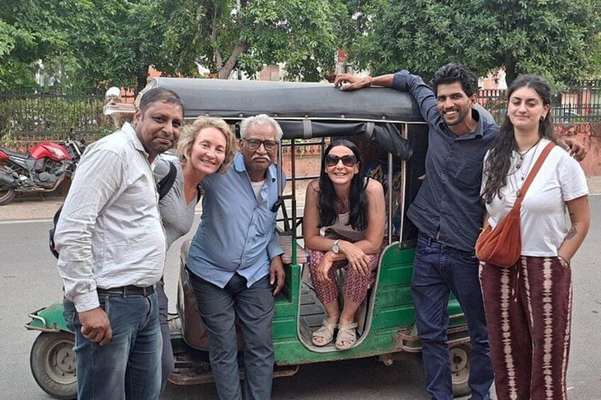 Un grupo de personas posando con un tuk-tuk verde. 2