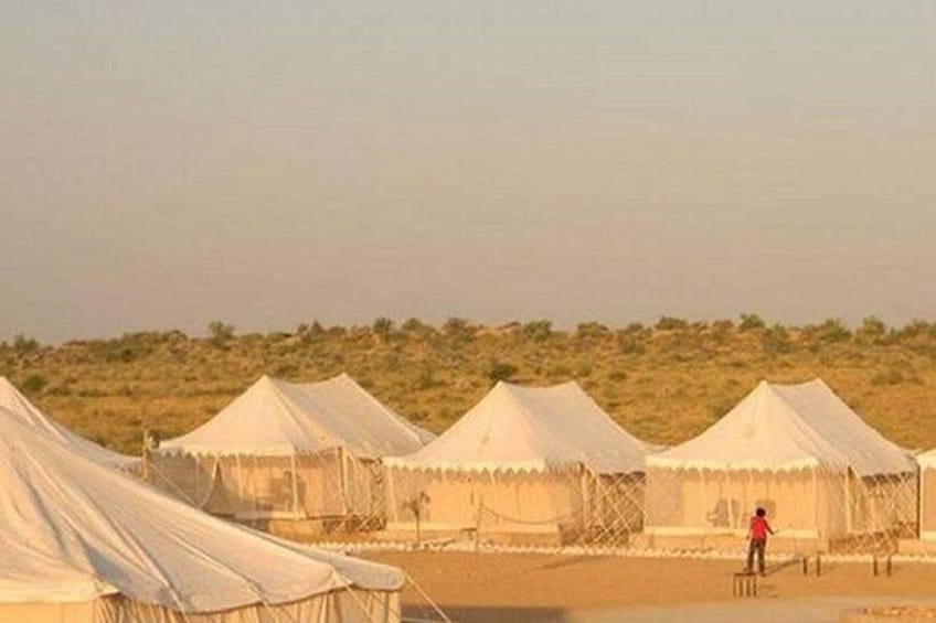 A desert landscape with multiple white tents. 4