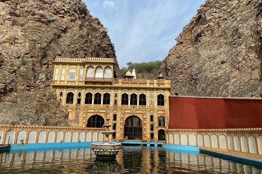 A historic building with ornate architecture, a reflective pool, and a rocky backdrop. 5