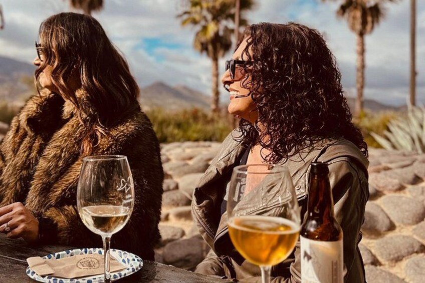 Two people sitting at a table with wine glasses and a bottle. 4