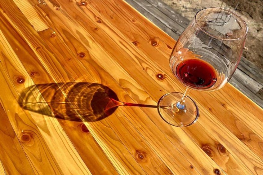 A wooden table with a wine glass containing red wine. 5