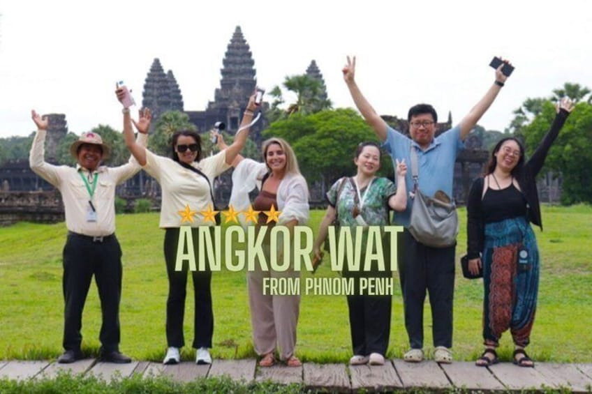 A group of people standing in front of Angkor Wat, with the temple's towers in the background. 1