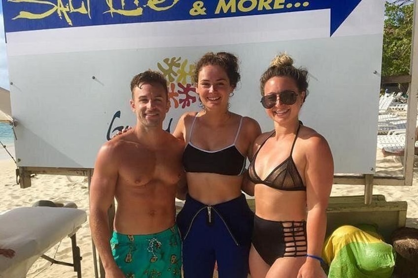 Three people standing in front of a beachside setup with a large sign. 3