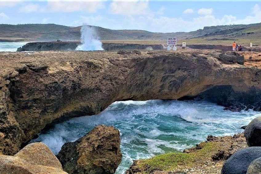 Formación rocosa costera con olas rompiendo a través de un arco natural. 3