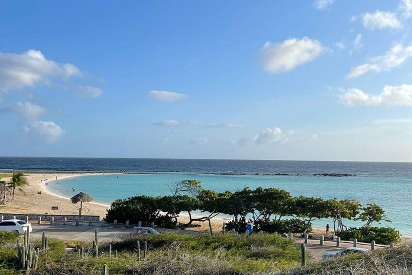 A beach with clear turquoise water, a sandy shore, and some vegetation. 3