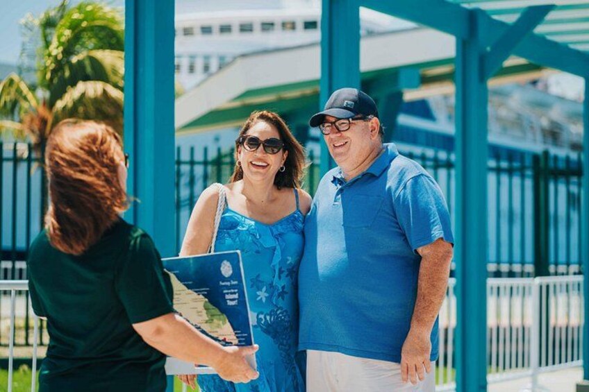 A person handing a brochure to a couple standing under a blue structure. 4