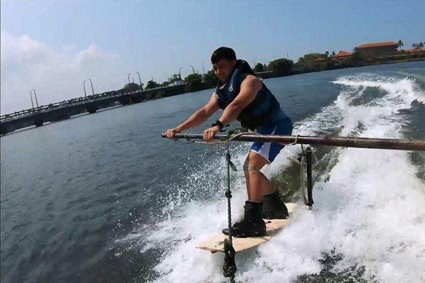 Iemand wakeboard achter op het water, met een brug op de achtergrond. 3