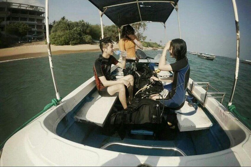 Ein Boot mit drei Personen an Bord, ein Sandstrand und ein klares blaues Meer. 2