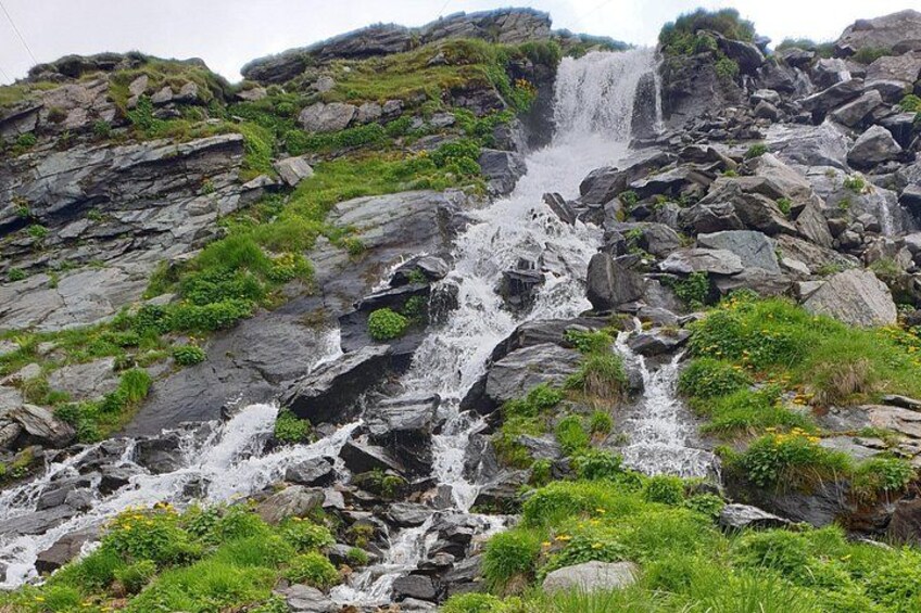 A waterfall cascading over rocky terrain with lush greenery. 5