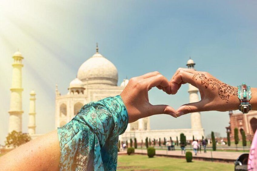 Two hands forming a heart shape in front of the Taj Mahal. 1