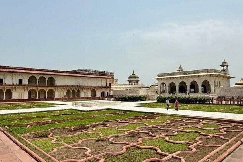 A historical building with arched walkways and a central garden with geometric patterns. 2