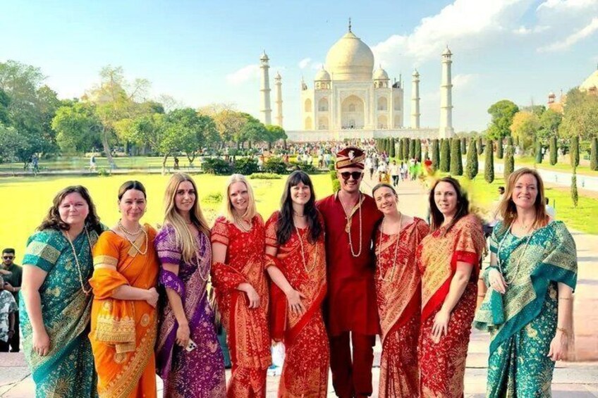 A group of people in traditional attire standing in front of the Taj Mahal. 5