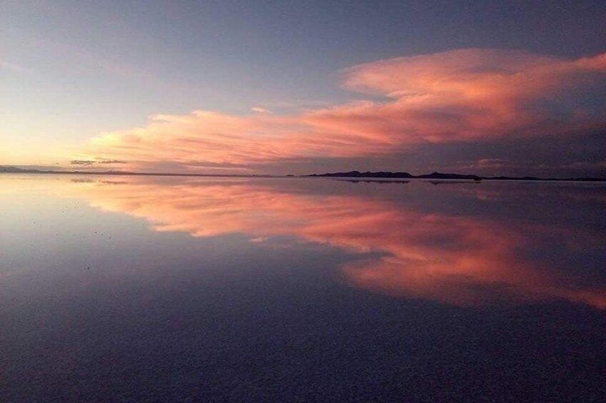 Una superficie acuática tranquila reflejando un cielo crepuscular con nubes. 1