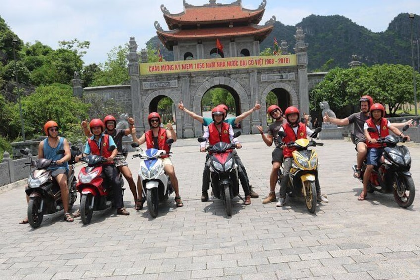 A group of people on motorcycles in front of a historic gate. 1