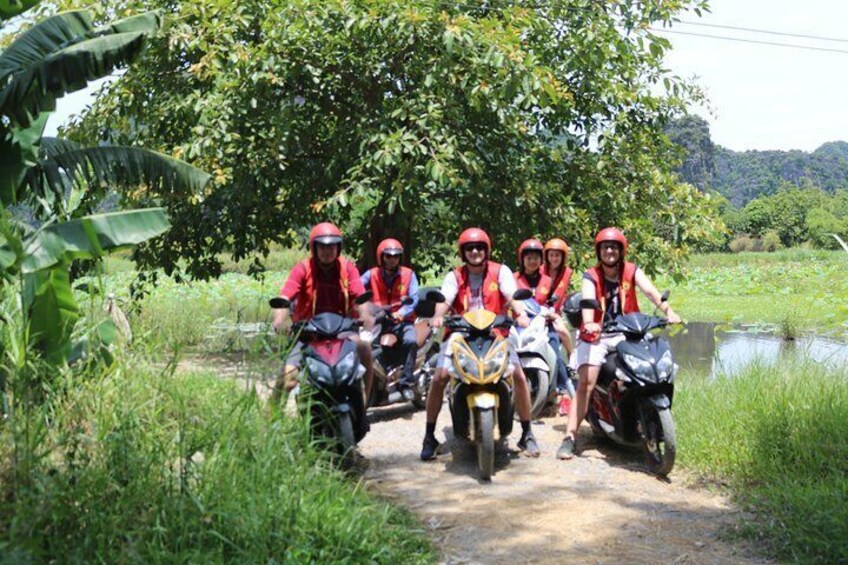 A group of people on motorcycles on a rural road surrounded by greenery. 4