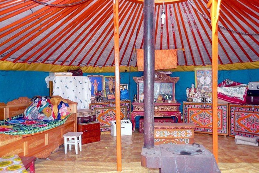 A traditional yurt with colorful decorations, a bed, and a central pillar. 4