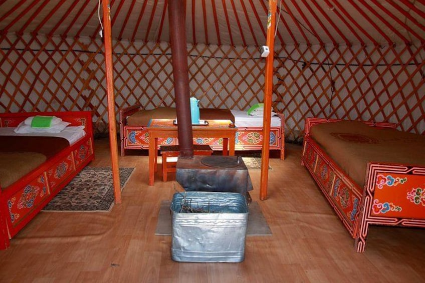A yurt interior with wooden beds, a central table, and a hanging chair. 3