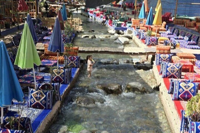 Un mercado a orillas del río con sombrillas de colores y asientos. 2