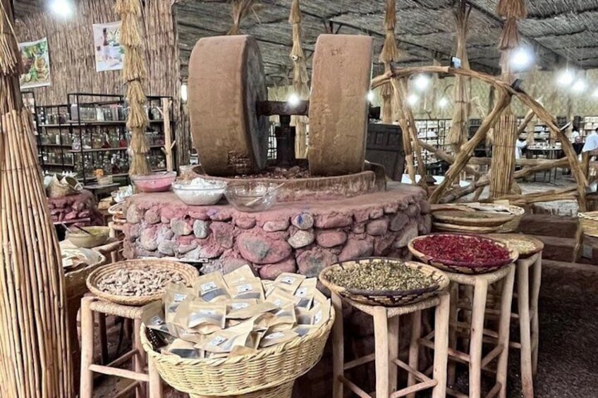 Un molino tradicional con muros de piedra y estructuras de madera, rodeado de cestas con granos y especias. 3
