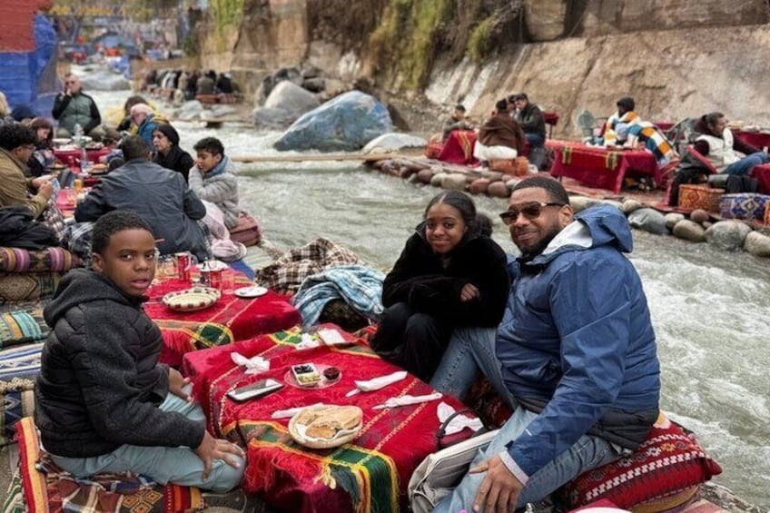 Personas sentadas en un bote con mesas dispuestas a lo largo de la orilla del río. 1