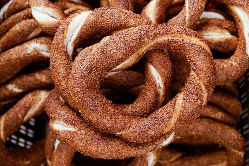 A close-up of twisted pretzel-like bread with sesame seeds. 1