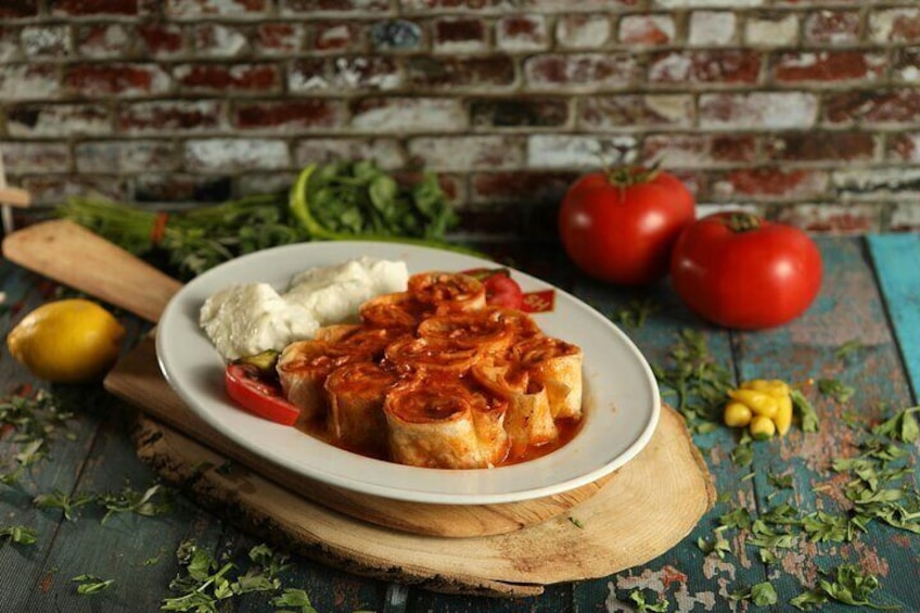 Une assiette de tomates farcies, accompagnée d’une sauce blanche, de tomates fraîches et d’herbes aromatiques, le tout présenté sur une planche en bois. 5
