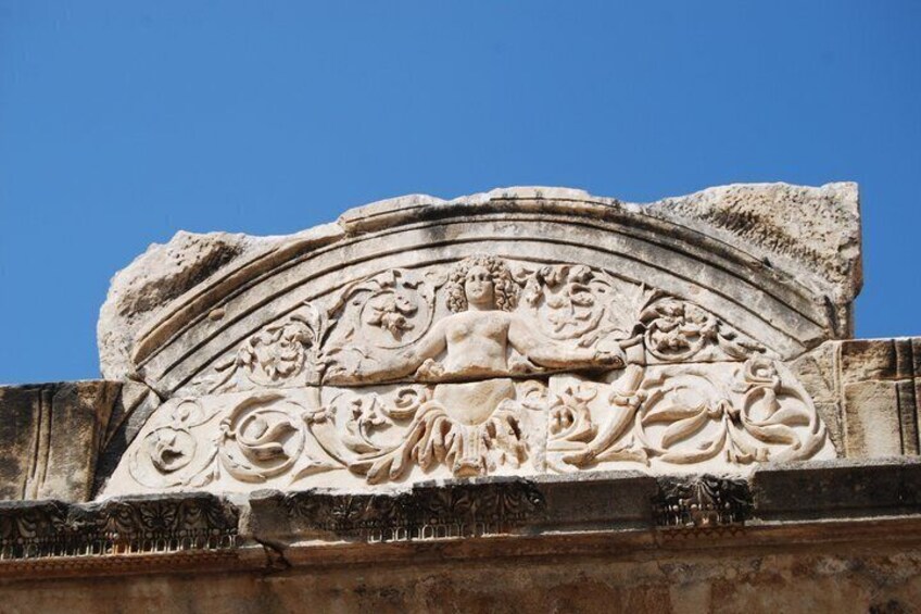 Ein Steinh Relief mit einer zentralen Figur und umlaufenden Zierelementen. 5