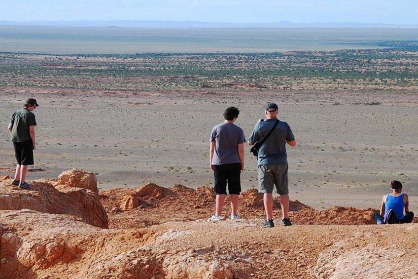 A group of people standing on a rocky outcrop overlooking a vast desert landscape. 4