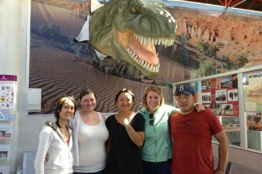 A group of people posing in front of a dinosaur exhibit. 5