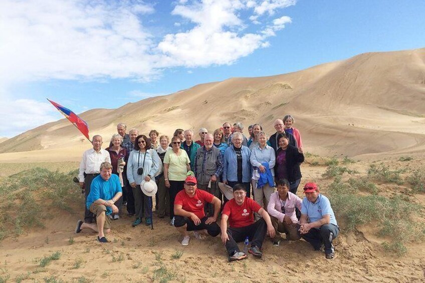 A group of people in a desert landscape with sand dunes in the background. 1