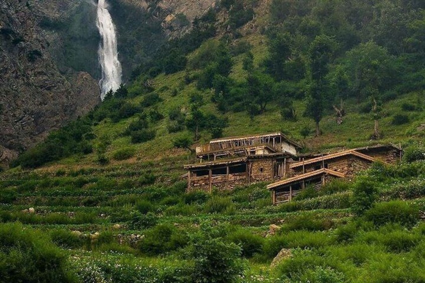 A rustic wooden house with a waterfall in the background. 5