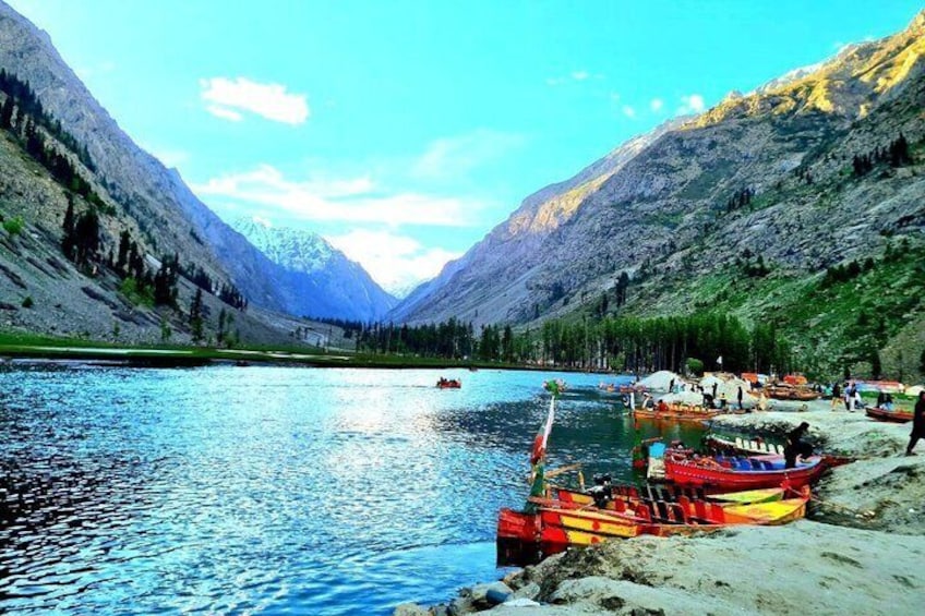 A lake surrounded by mountains, boats docked on the shore, and a clear sky. 2