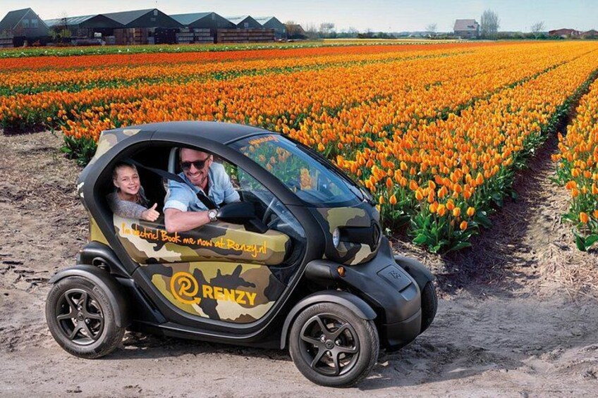 A small vehicle with a camouflage pattern parked in a field of orange flowers. 1
