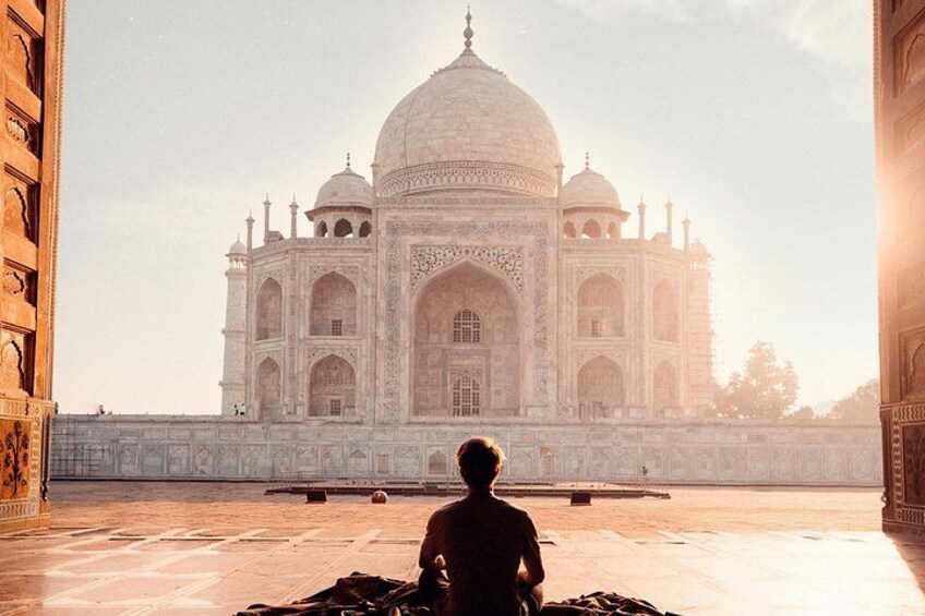 A person sitting on a bench facing the Taj Mahal. 4