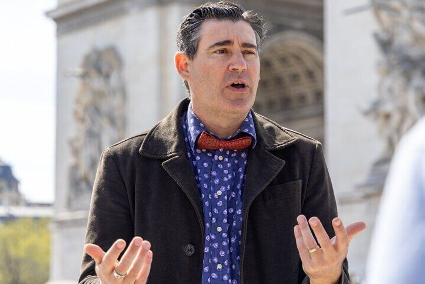 A person in a coat and bow tie standing with hands raised. 4