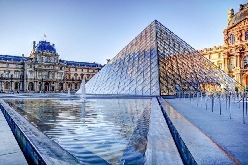 The Louvre Pyramid, a glass and metal structure, with a fountain in front and classical buildings in the background. 2