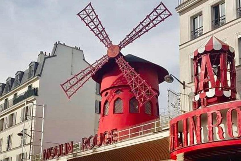 Een rode windmolen met de tekst 'Moulin Rouge' voor een gebouw. 3