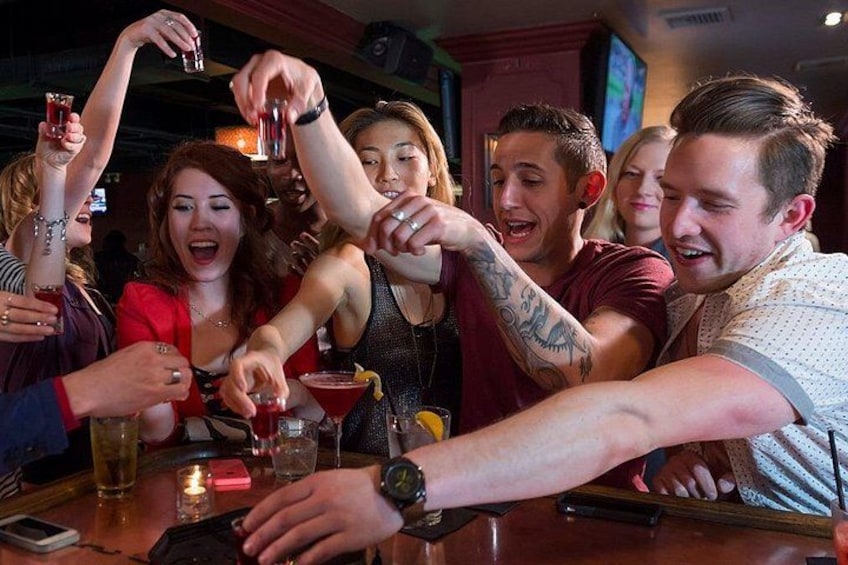 Un groupe de personnes trinquant avec des boissons dans un bar. 2