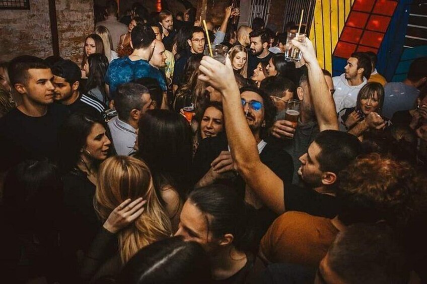 Un evento interior concurrido donde personas levantan las manos, posiblemente animando o celebrando. 1