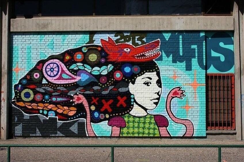 A colorful mural with a woman's face and a snake on a wall. 3