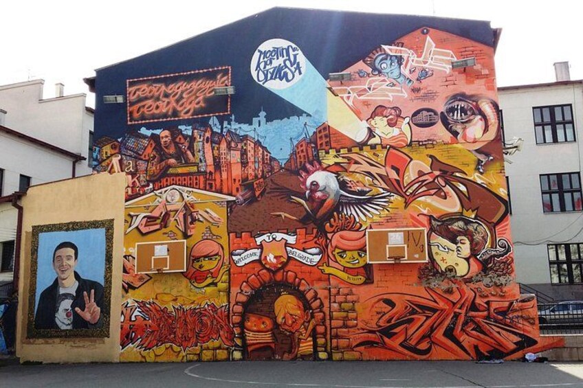 A colorful mural on a building with various artistic elements and a basketball court. 4