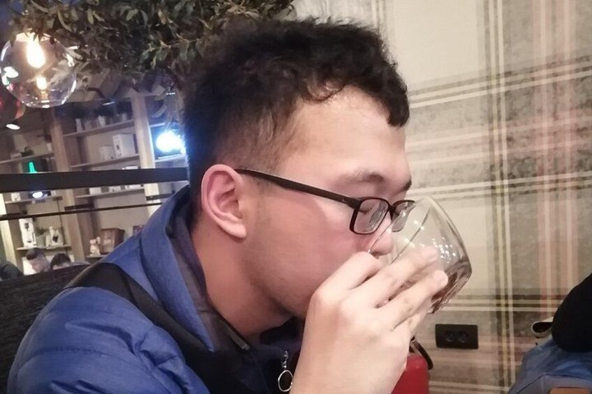 A person sitting indoors, holding a glass. 2
