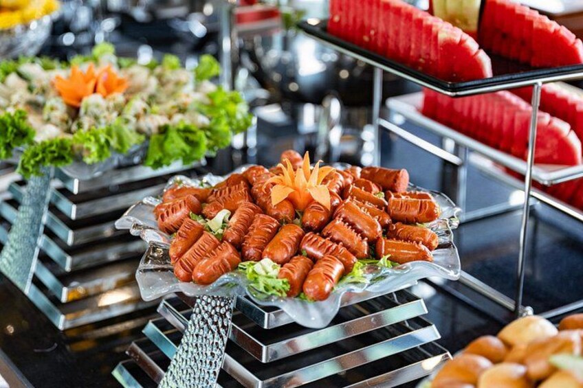 A buffet with various food items including sausages, salads, and watermelon slices. 2