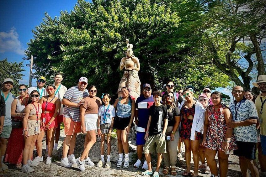 A group of people posing in front of a statue. 4