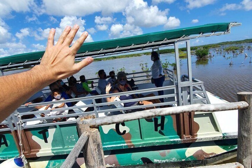 A boat with people on it, a hand reaching out, and water in the background. 2