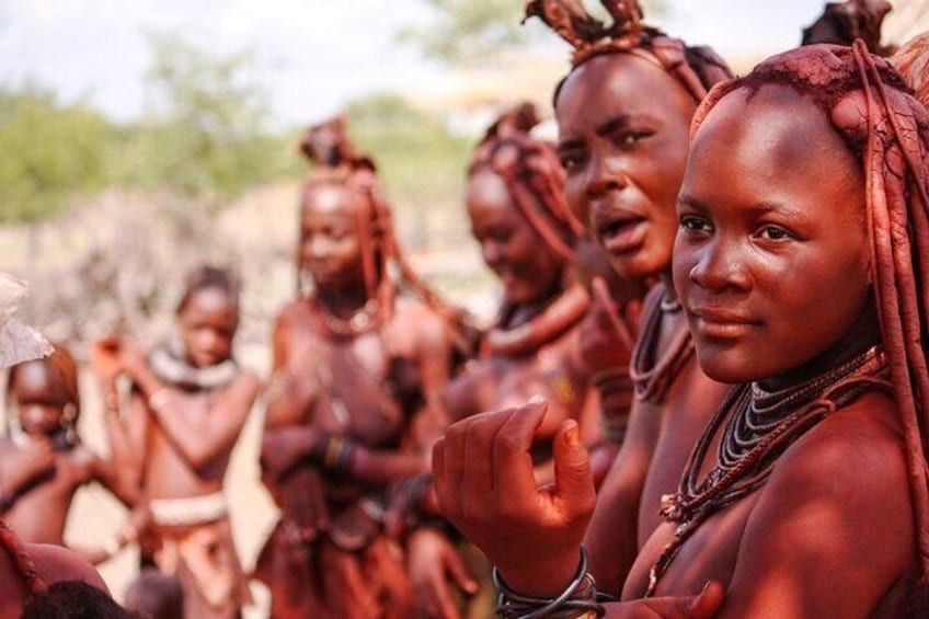 A group of people in traditional attire, with one person in the foreground gesturing. 1