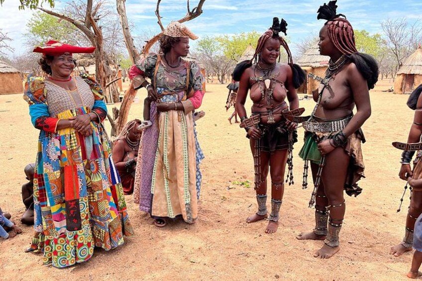 A group of people in traditional attire standing in a dry, open landscape with sparse vegetation and a clear sky. 2