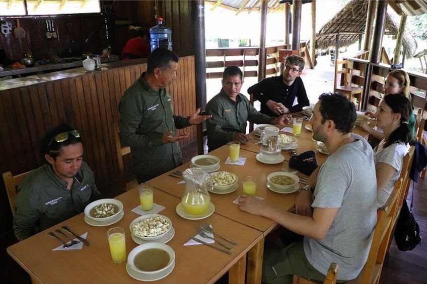 A group of people dining at a wooden table with bowls of food and drinks. 3